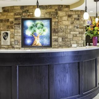 A modern reception desk with artwork and flowers, featuring stylish lighting.