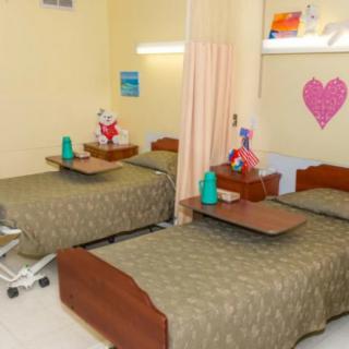 A hospital room with twin beds, decorated with colorful items and separated by a curtain.