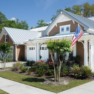 A suburban house with a manicured garden and an American flag displayed out front.
