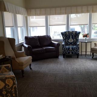 A cozy living room with various chairs and a sofa near large windows.