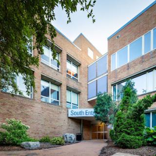 Entrance of a modern brick building with landscaped greenery.