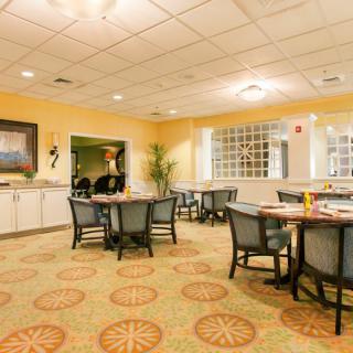 A cozy dining area with neatly arranged tables and chairs, warm lighting, and elegant decor.