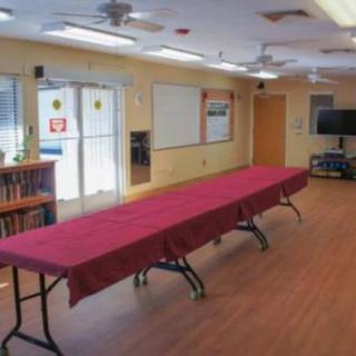 A conference room with a long, red-covered table, whiteboards, and a television.