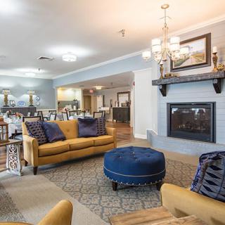 A stylish living room with yellow sofas, a blue ottoman, and a cozy fireplace.
