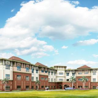 A large residential building with a brick facade under a partly cloudy sky.