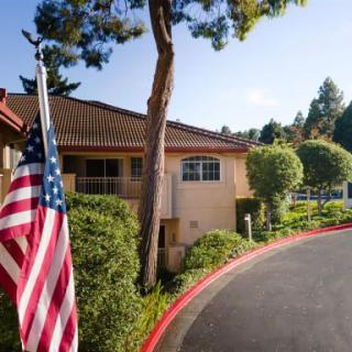 A building with an American flag and surrounding greenery under a clear sky.