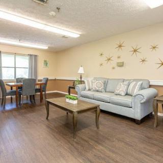 A cozy living room setup featuring a light blue sofa, wooden coffee table, and dining area.
