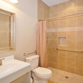 A modern bathroom featuring a sink, toilet, and tiled shower area with a curtain.
