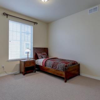 A minimalist bedroom with a single bed and nightstand next to a window.