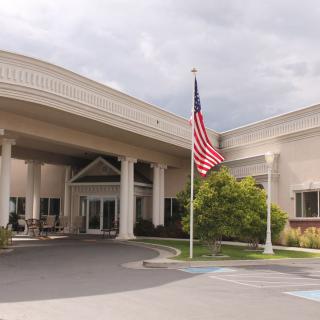 A building entrance with a prominent American flag flying on a cloudy day.