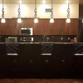A modern kitchen with pendant lighting and bar stools at the counter.