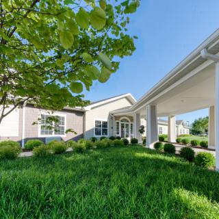 A modern building with a landscaped entrance, surrounded by lush greenery.