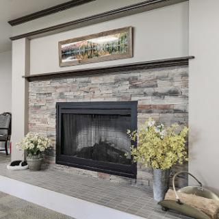 A beautifully designed living room featuring a modern fireplace with a stone surround, complemented by artwork and decorative flowers.