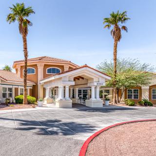 A sunny day at the entrance of a stylish building surrounded by palm trees.