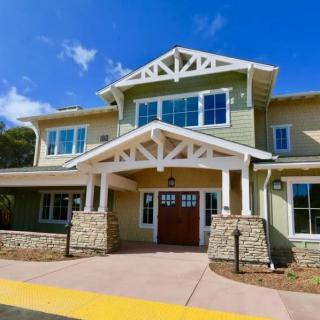 A modern two-story house with a stone facade and large windows under a clear blue sky.