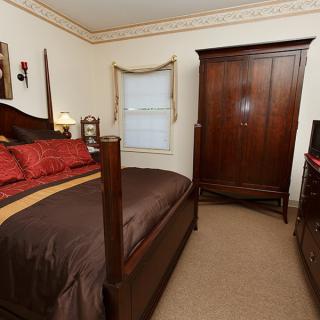 A cozy bedroom with traditional decor, featuring a wooden bed and wardrobe.