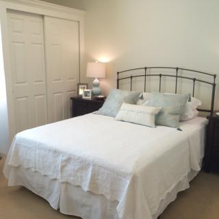 A cozy and well-decorated bedroom with a neatly made bed, soft pillows, and a lamp on the nightstand.