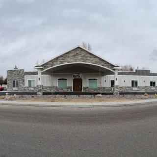 A front view of a building with a stone facade under a cloudy sky.