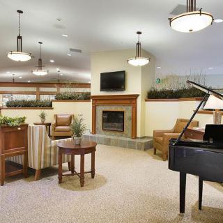 A modern lounge area featuring a piano, comfortable seating, and a cozy fireplace.