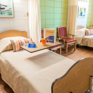 A well-lit hospital room with two beds, featuring comfortable furnishings and medical equipment.