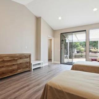 A minimalist bedroom with wooden furniture and large windows allowing natural light.