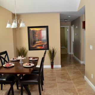 A cozy dining area featuring a wooden table set for a meal, complemented by contemporary wall art and decorative plants.
