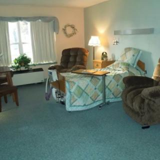 A cozy room featuring a bed, armchair, and natural lighting from the window.