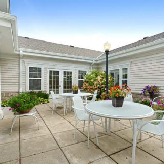 A cozy courtyard with white patio furniture and vibrant plants.
