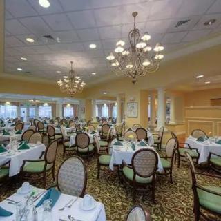 An elegant dining room with neatly arranged tables and chairs, decorated with chandeliers.
