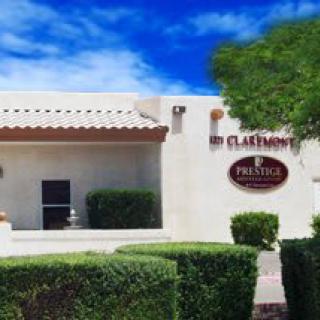 A southwestern-style building surrounded by neatly trimmed bushes and a small tree.