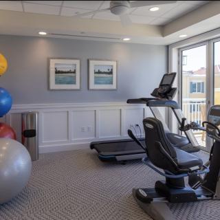 A small fitness room featuring a treadmill, stationary bike, and exercise balls.