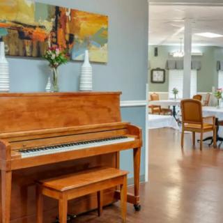 A cozy interior with a wooden piano and a dining area in the background.