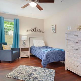 A cozy bedroom with a single bed, blue bedding, and matching curtains near a window.