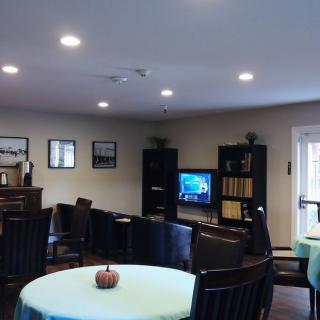 A cozy living room with chairs, tables, a television, and a bookshelf.