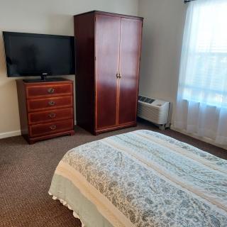 A cozy bedroom with a wardrobe, dresser, and television.