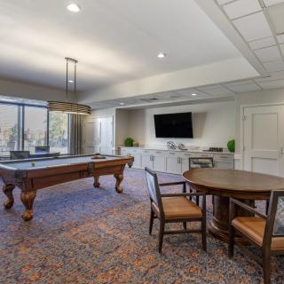 A modern game room featuring a billiards table, a television, and comfortable seating.