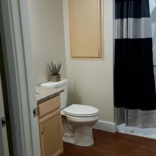 A clean and modern bathroom with a toilet, wooden cabinet, and striped shower curtain.