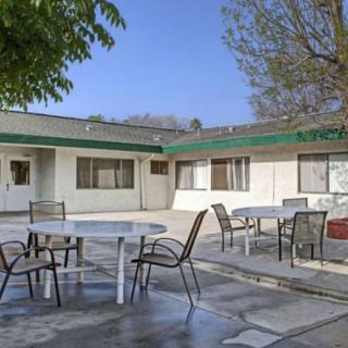 An outdoor patio area with round tables, chairs, and surrounding buildings on a sunny day.