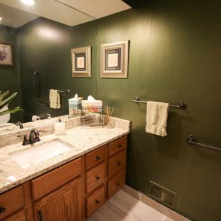 A cozy bathroom with green walls, a wooden cabinet, and decorative items on the countertop.