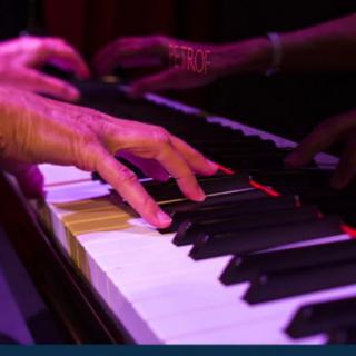 Close-up of hands playing the piano under stage lighting.