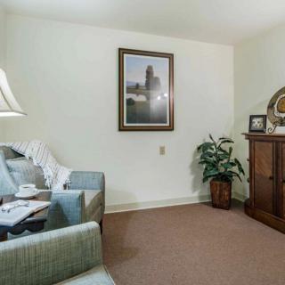 A cozy living room featuring a sofa, lamp, artwork on the wall, a plant, and a wooden cabinet.