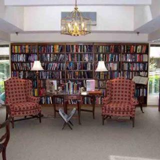A cozy library reading room with bookshelves, armchairs, and warm lighting.