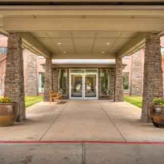 The welcoming entrance of a modern facility, featuring elegant stone details and well-kept landscaping.