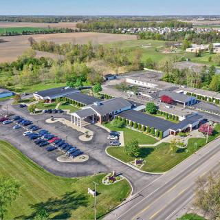 Aerial view of a suburban complex with multiple buildings, parking lots, and surrounding fields.