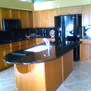 A modern kitchen with wooden cabinets and a central island featuring black granite countertops.