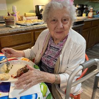 An elderly woman enjoying a meal at home.