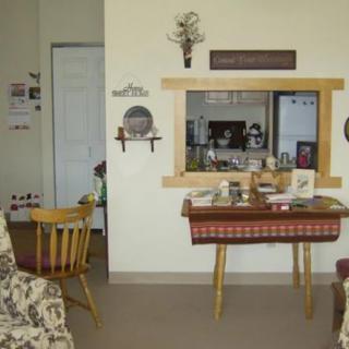 A cozy living room featuring a table with decorative items, a chair, and wall art.