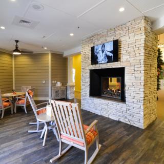 A cozy lounge with rocking chairs, a brick fireplace, and a TV.