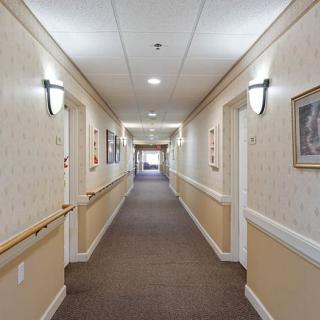 A well-lit hallway with carpet, handrails, and framed pictures on the walls.