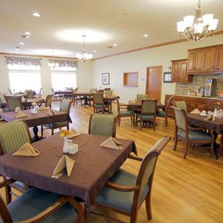 A spacious dining area with neatly arranged tables and chairs, featuring elegant chandeliers.